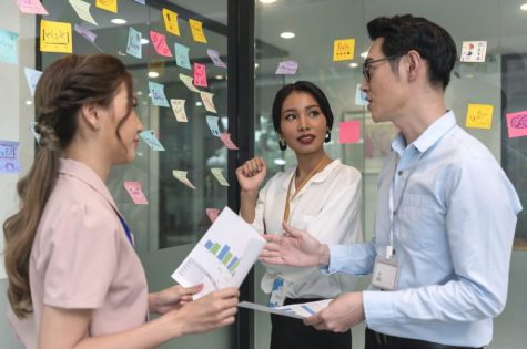 Asian business people meeting at office and use post it notes to share idea. Brainstorming concept. Sticky note on glass wall.